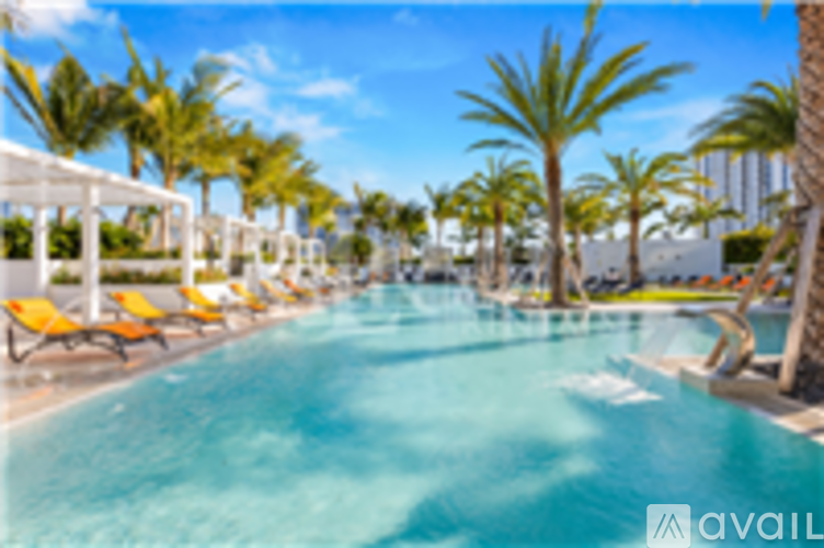 A pool surrounded by palm trees and lounge chairs.