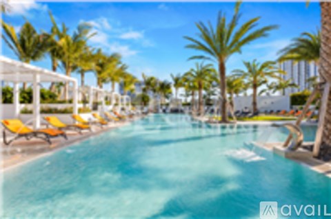 A pool surrounded by palm trees and lounge chairs.