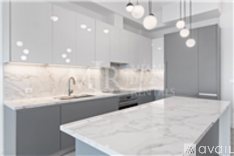 A kitchen with a marble countertop and grey cabinets.