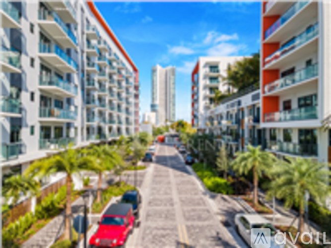 A street with a red car and buildings on both sides.