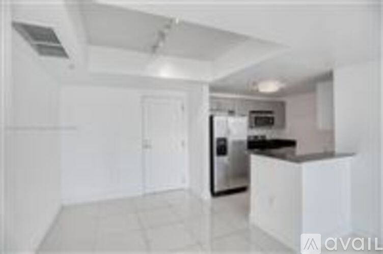 A kitchen with white cabinets and a stainless steel refrigerator.