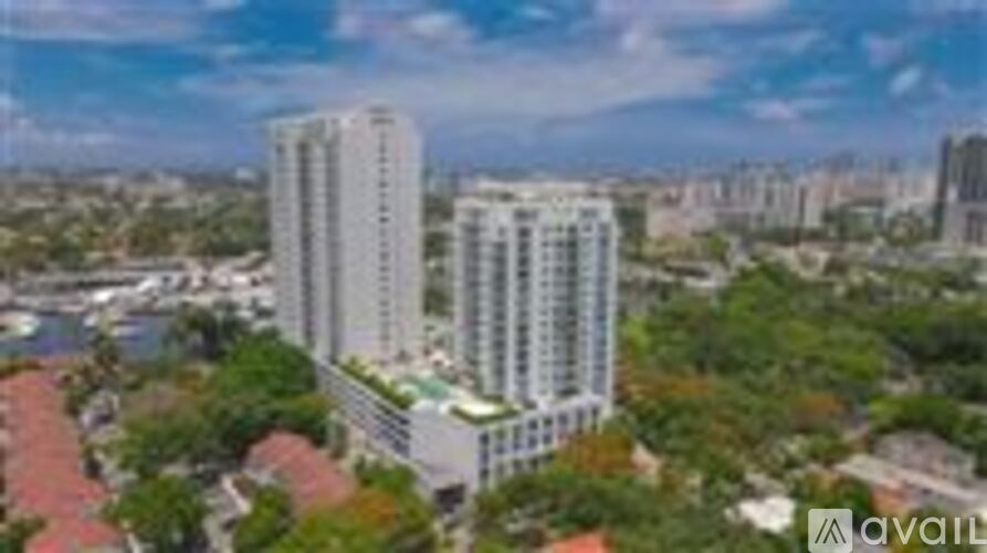 A tall white building with a green roof is surrounded by trees.