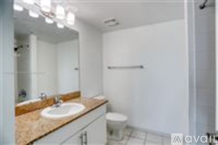 A bathroom with a sink, mirror, toilet and a towel bar.