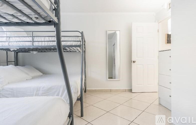 A white bedroom with a bunk bed and a white wardrobe.