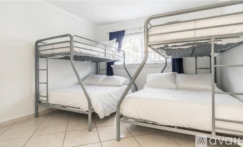 Two bunk beds in a room with white walls.