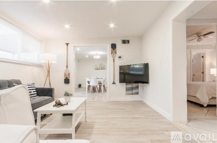 A modern living room with a black couch, white chairs, and a television mounted on the wall.