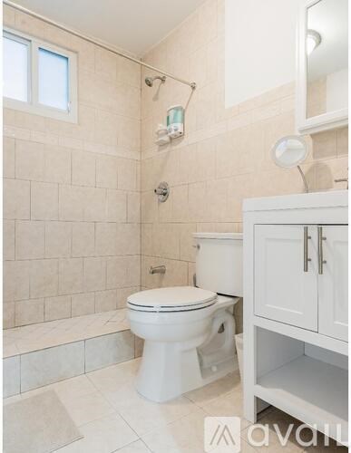 A white toilet in a tiled bathroom with a cabinet above it.