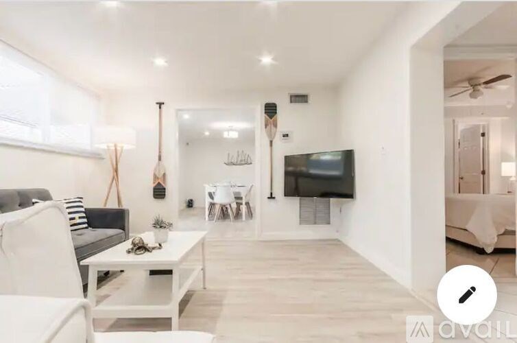 A modern living room with a grey sofa, a white coffee table, and a television mounted on the wall.