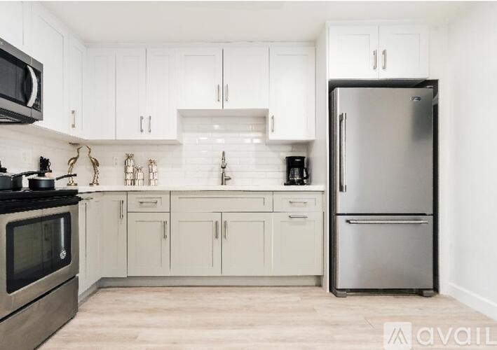 A kitchen with white cabinets and a stainless steel refrigerator.