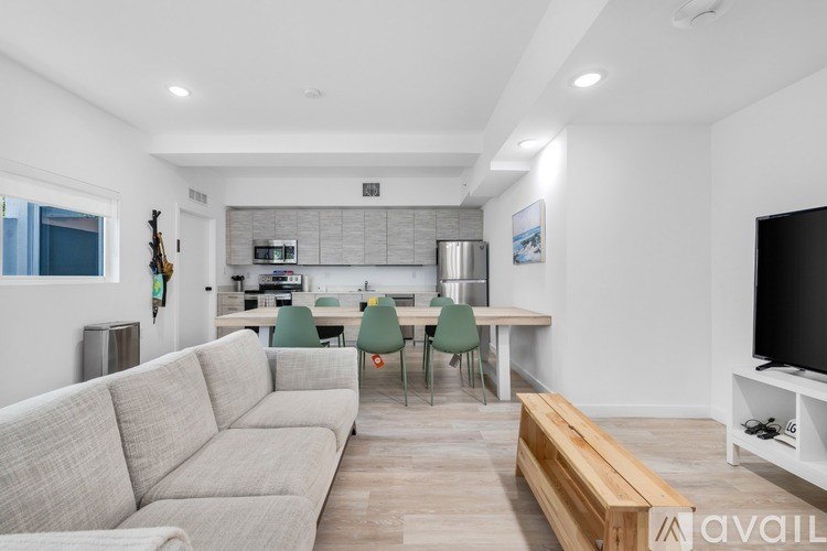 A living room with a couch, chairs, and a television.