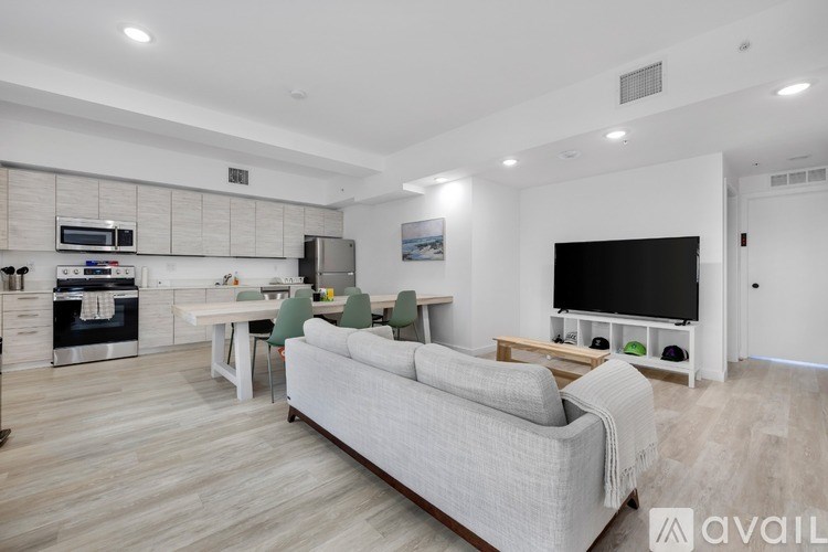 A modern living room with a grey sofa and a kitchen area in the background.