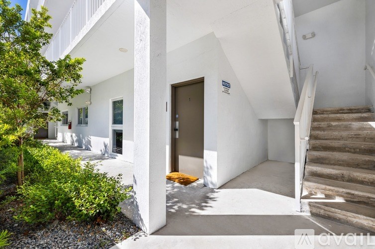 A white building with a brown door and stairs leading up to it.