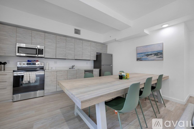 A modern kitchen with a wooden table and green chairs.