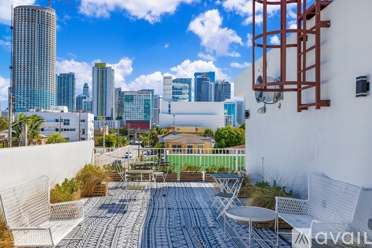 A balcony with chairs and a table overlooks a city skyline.