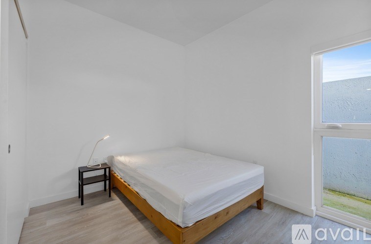 A bedroom with a bed, nightstand, and window.