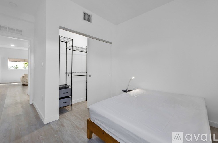 A bedroom with a bed, nightstand, and a window.