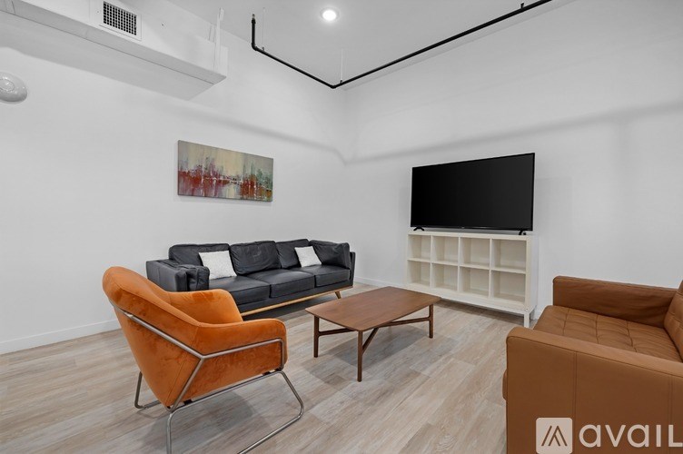 A living room with a black couch, a brown chair, and a brown sofa.