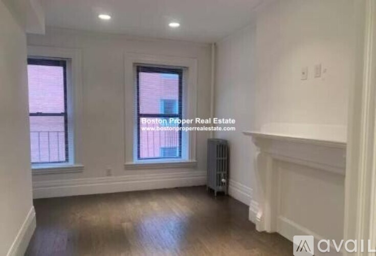 A room with wooden floors and white walls, with a window and a radiator.