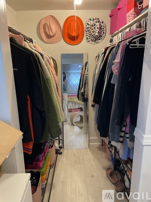 A room with a lot of clothes hanging up and a mirror in the middle.