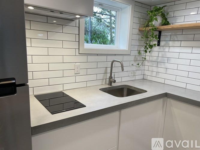 A kitchen with a white tiled wall and a window.