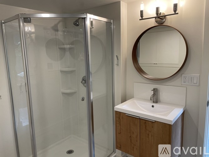 A bathroom with a sink, mirror, and shower.
