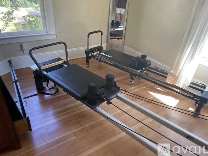 A pilates reformer is set up in a room with a mirror and a window.