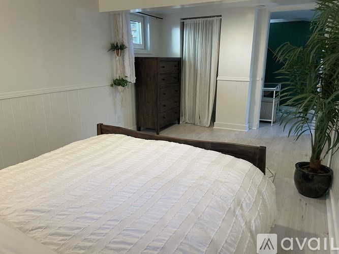 A bedroom with a large bed and a wooden dresser.