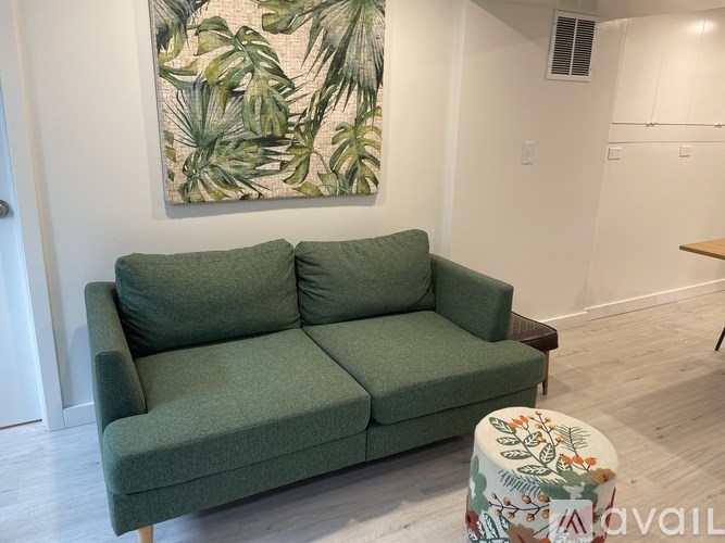 A green couch with a floral patterned ottoman in front of it.