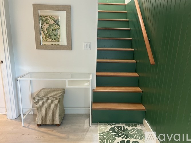 A staircase with a green wall and a wooden handrail.