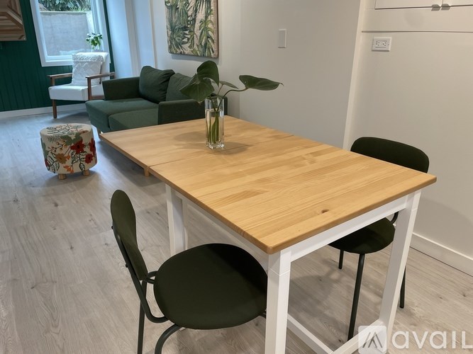A dining table with two chairs and a vase with a plant on it.
