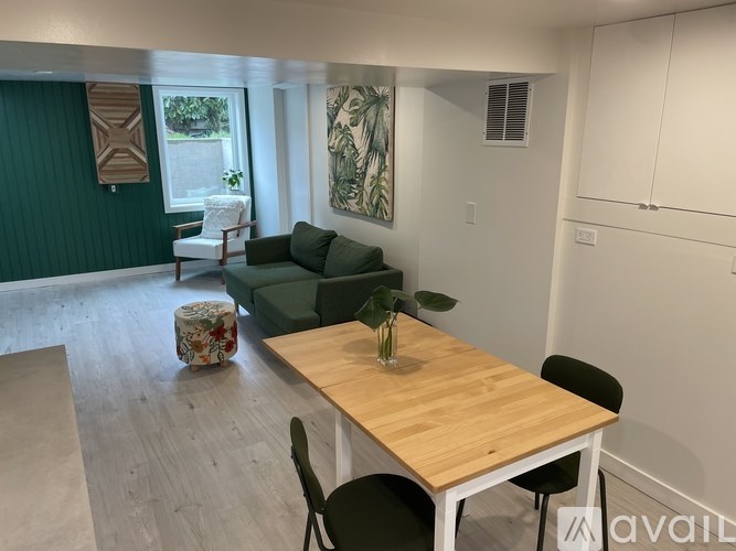 A room with a wooden table and chairs, a green sofa, and a painting on the wall.