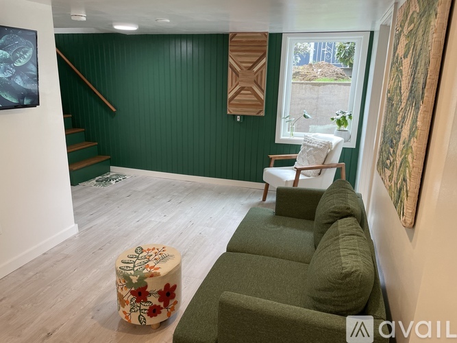 A living room with a green couch and a floral ottoman.