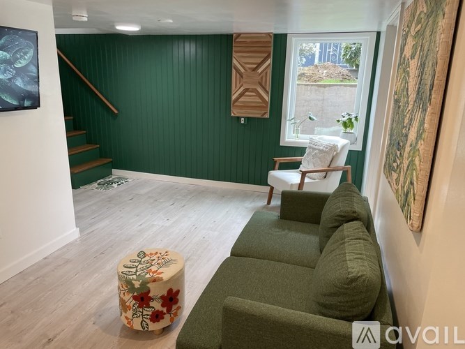 A living room with a green couch and a floral ottoman.