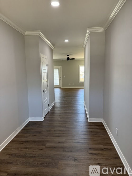 A long hallway with wood floors and white walls.