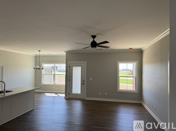 A spacious room with a ceiling fan and sliding glass doors leading to a balcony.