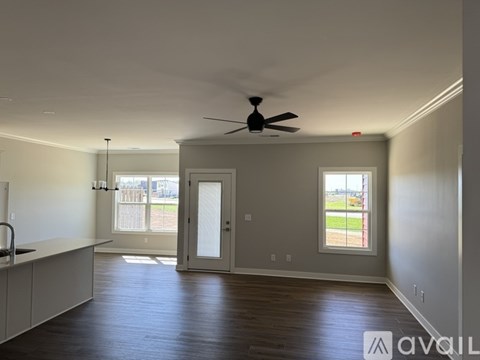 A spacious room with a ceiling fan and sliding glass doors leading to a balcony.