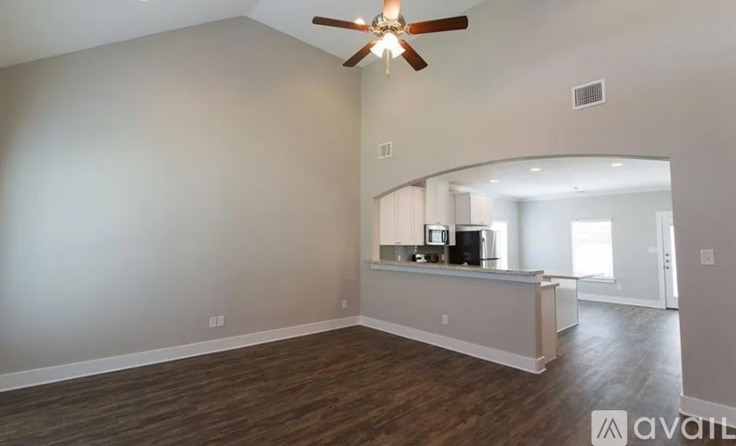 A spacious room with a ceiling fan and a counter in the middle.