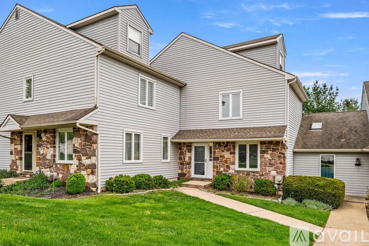 A house with a grey siding and a stone pillar in front of it.