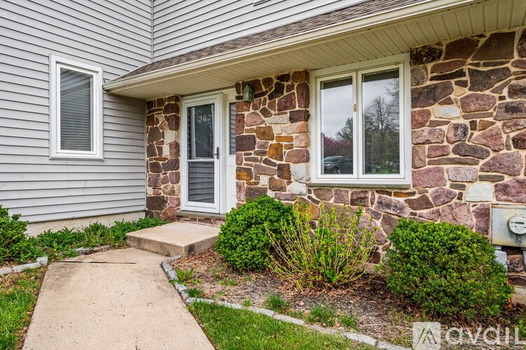 A house with a grey siding and a stone pillar.