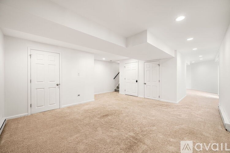 A spacious room with carpeted floor and white walls.