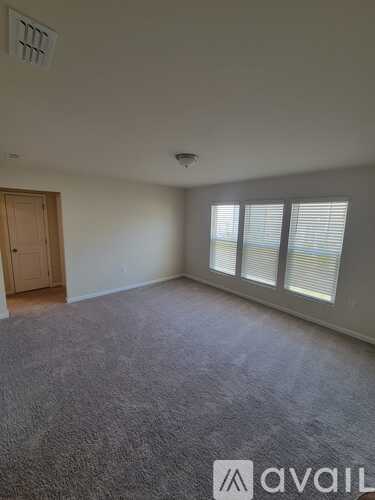 A room with a carpeted floor, a door, and a window with blinds.