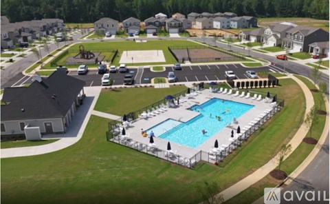 A large outdoor swimming pool surrounded by a fence and lounge chairs.