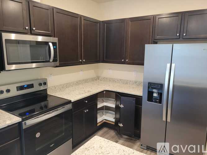 A kitchen with black cabinets and a stainless steel refrigerator.