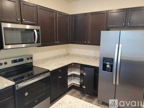 A kitchen with black cabinets and a stainless steel refrigerator.