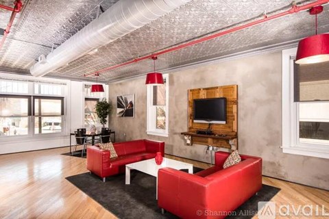 A living room with a red couch and a television on a wooden stand.