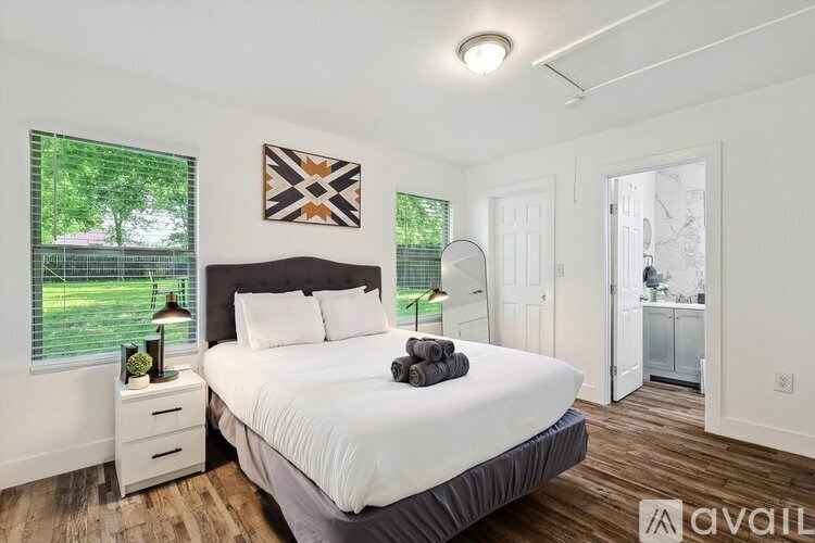 A bedroom with a large bed and a window overlooking a green lawn.