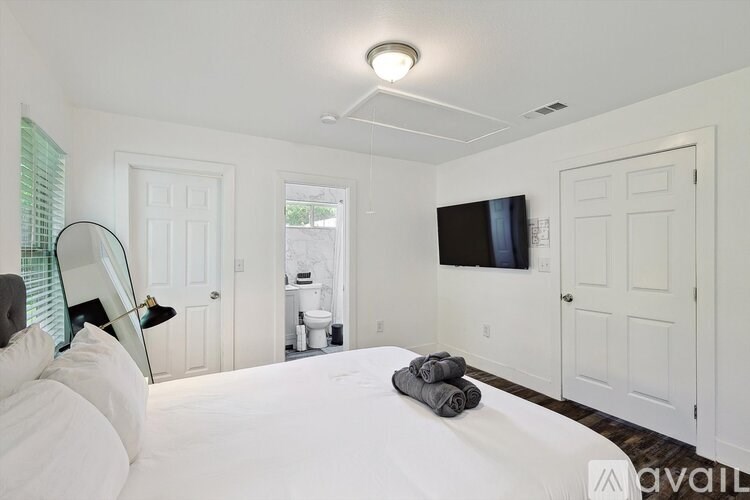 A bedroom with a bed, a television, and a window with blinds.