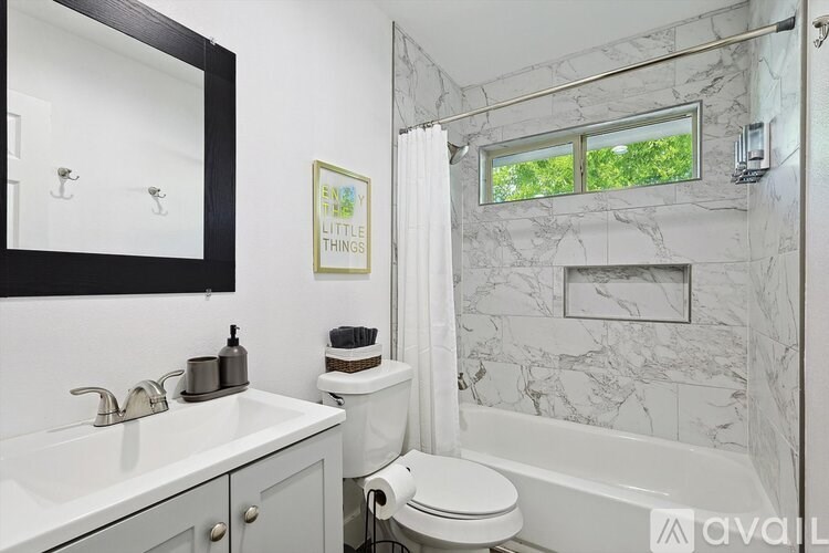 A bathroom with a marble wall and a white toilet.