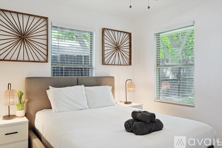 A bedroom with a white bed and two lamps.