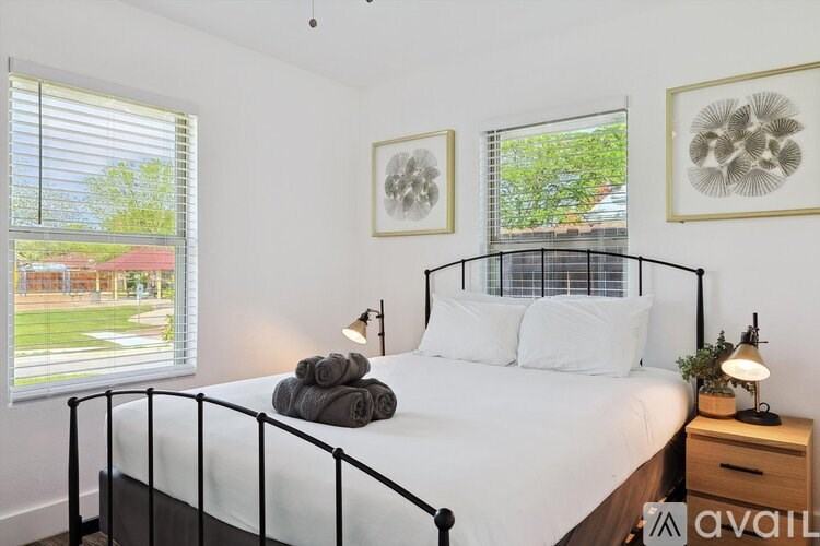 A bedroom with a white bed and two framed artworks on the wall.